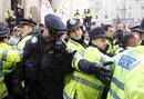 Varios agentes de polic&iacute;a se protegen de la pintura que les tira un grupo de activistas