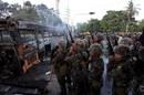 Soldados tailandeses toman posiciones frente a un autob&uacute;s incendidado.