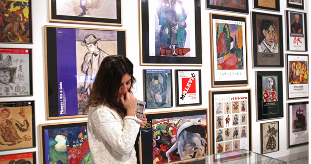 Una visitante junto a un grupo de carteles expuestos en el Museo Picasso.