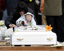 Una mujer y su hijo dejan una rosa sobre un peque&ntilde;o f&eacute;retro blanco en el funeral de Estado.