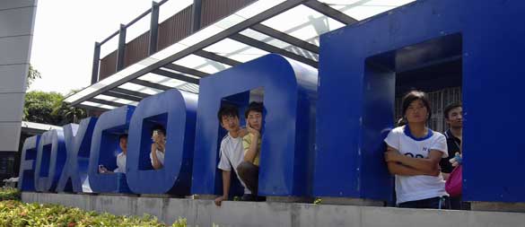 Workers stand at the gate of a Foxconn factory in the township of Longhua in Shenzhen